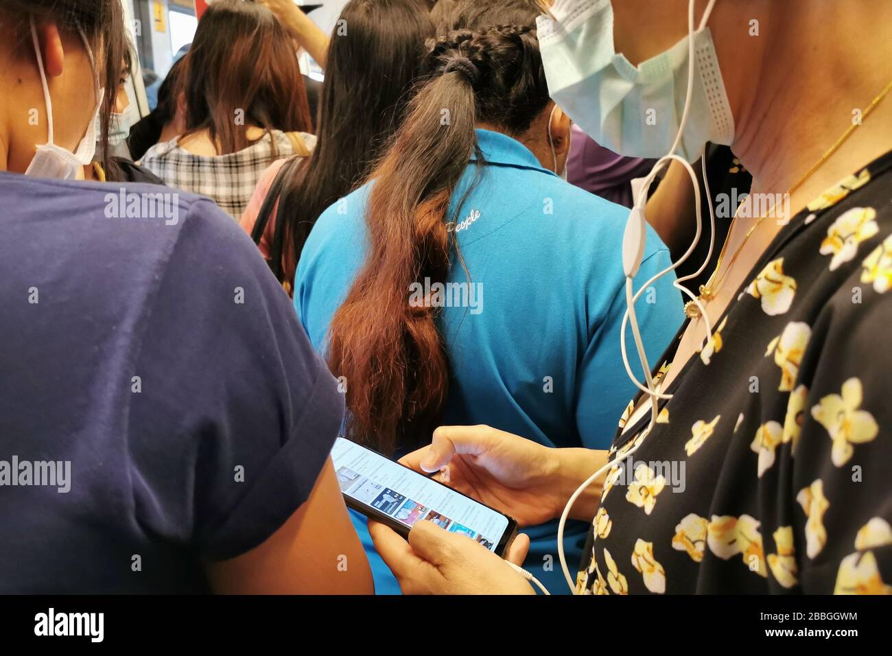 Bangkok, Thailand - 14. März 2020: asiatische Passagiere im Skytrain öffentliche Verkehrsmittel tragen Hygienemaske und werden Pandemie-Nachrichten lesen Stockfoto
