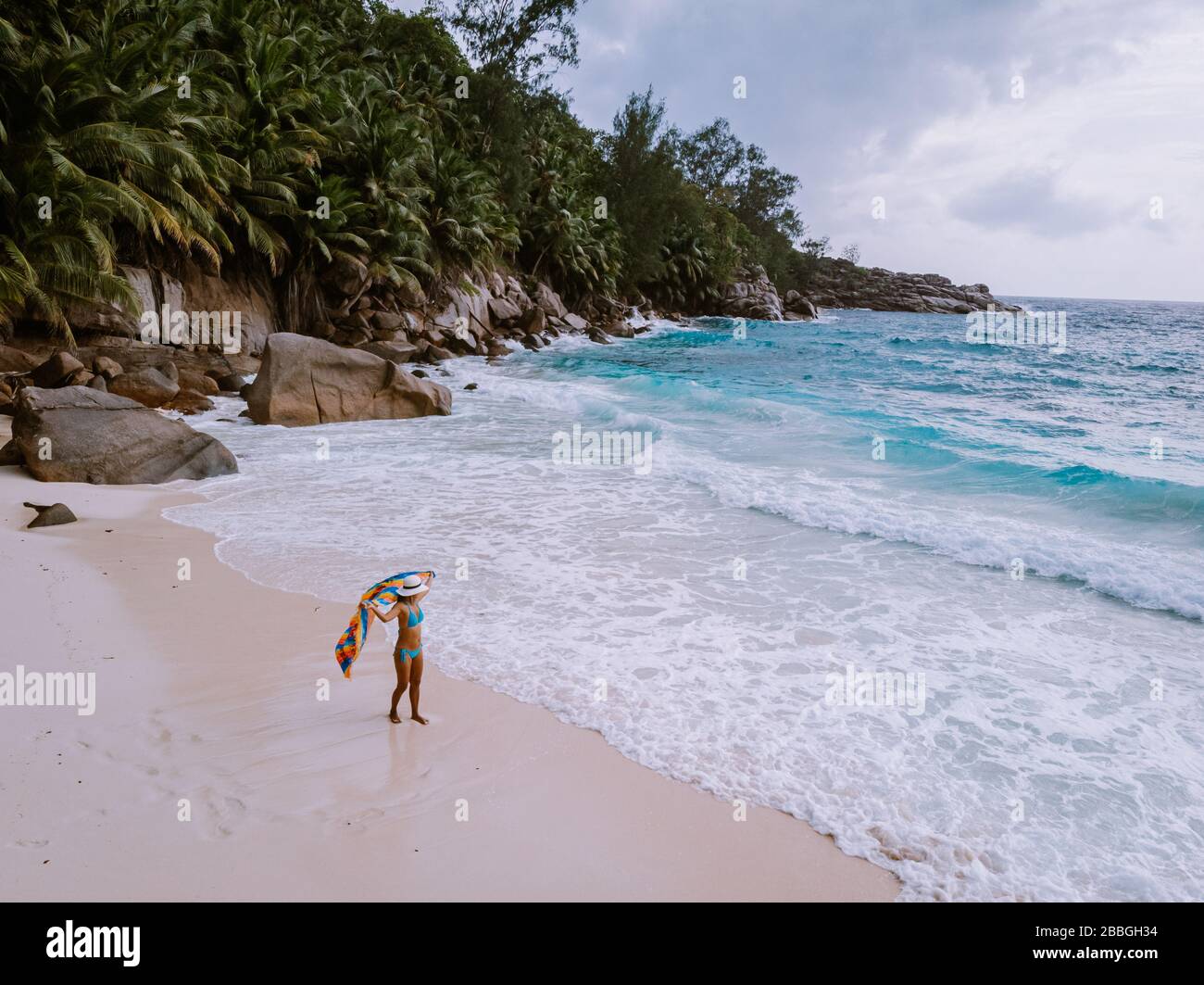 Petite Anse Mahe Seychellen, junge Frau am Strand, mittelalte Asiatin, die am tropischen Strand der Seychellen spaziert Stockfoto