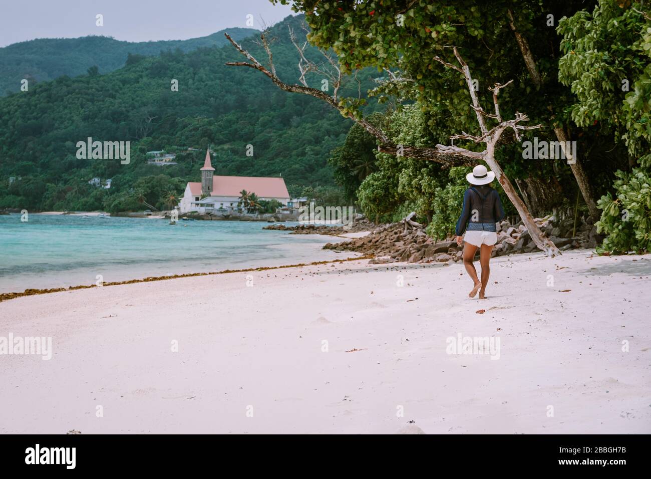 Petite Anse Mahe Seychellen, junge Frau am Strand, mittelalte Asiatin, die am tropischen Strand der Seychellen spaziert Stockfoto