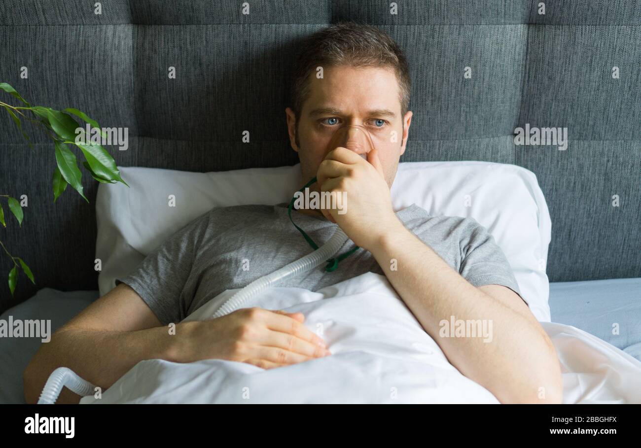 Kranker Mann mit Inhalatormaske auf dem Gesicht im Bett. Konzept zur Vorbeugung von Coronavirus. Stockfoto