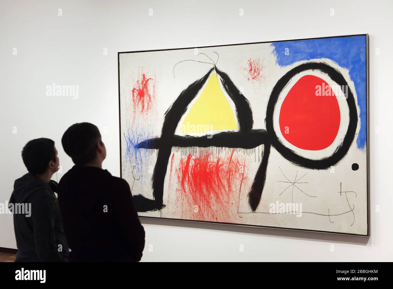 Besucher vor dem Gemälde des spanischen Modernisten Malers Joan Miró mit dem Titel "Figur vor der Sonne" (1968), das in der Fundació Joan Miró (Joan Miró Stiftung) in Barcelona, Katalonien, Spanien ausgestellt ist. Stockfoto