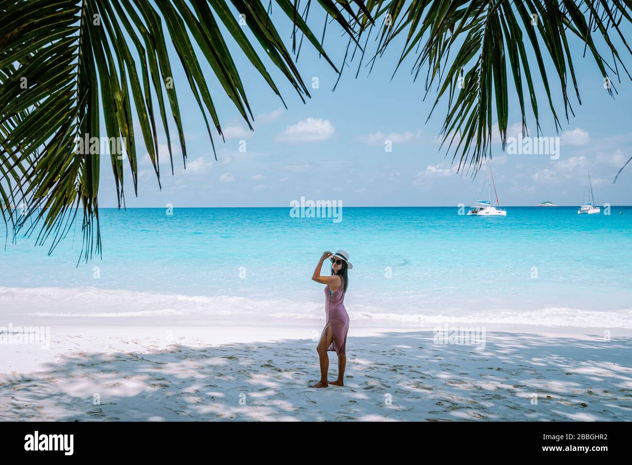 Petite Anse Mahe Seychellen, junge Frau am Strand, mittelalte Asiatin, die am tropischen Strand der Seychellen spaziert Stockfoto