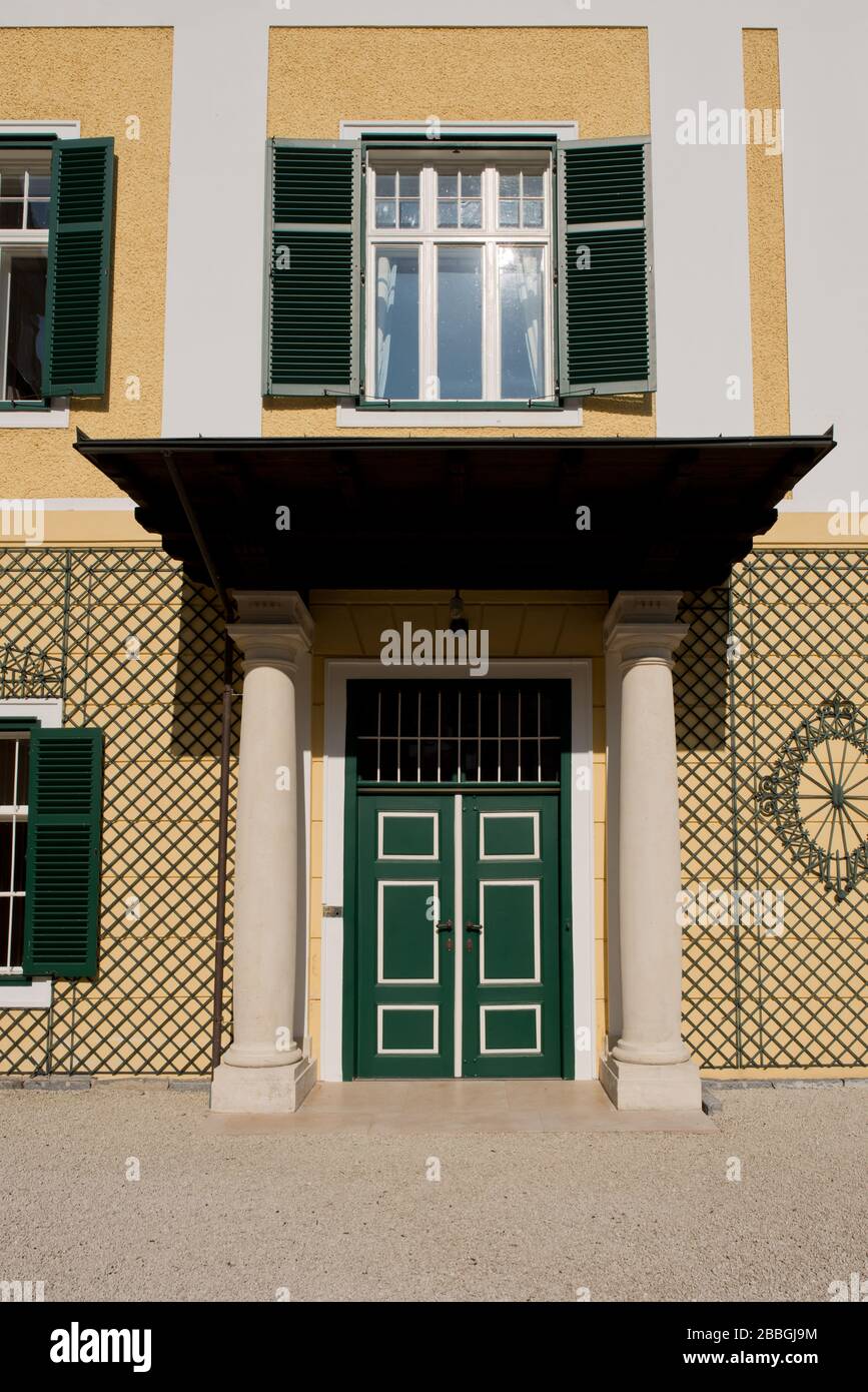 Holzgitter an gelber Fassade des Biedermeier Schlosses mit Fenstern und grünen Fensterläden, Schloss Kogl, Oberösterreich Stockfoto