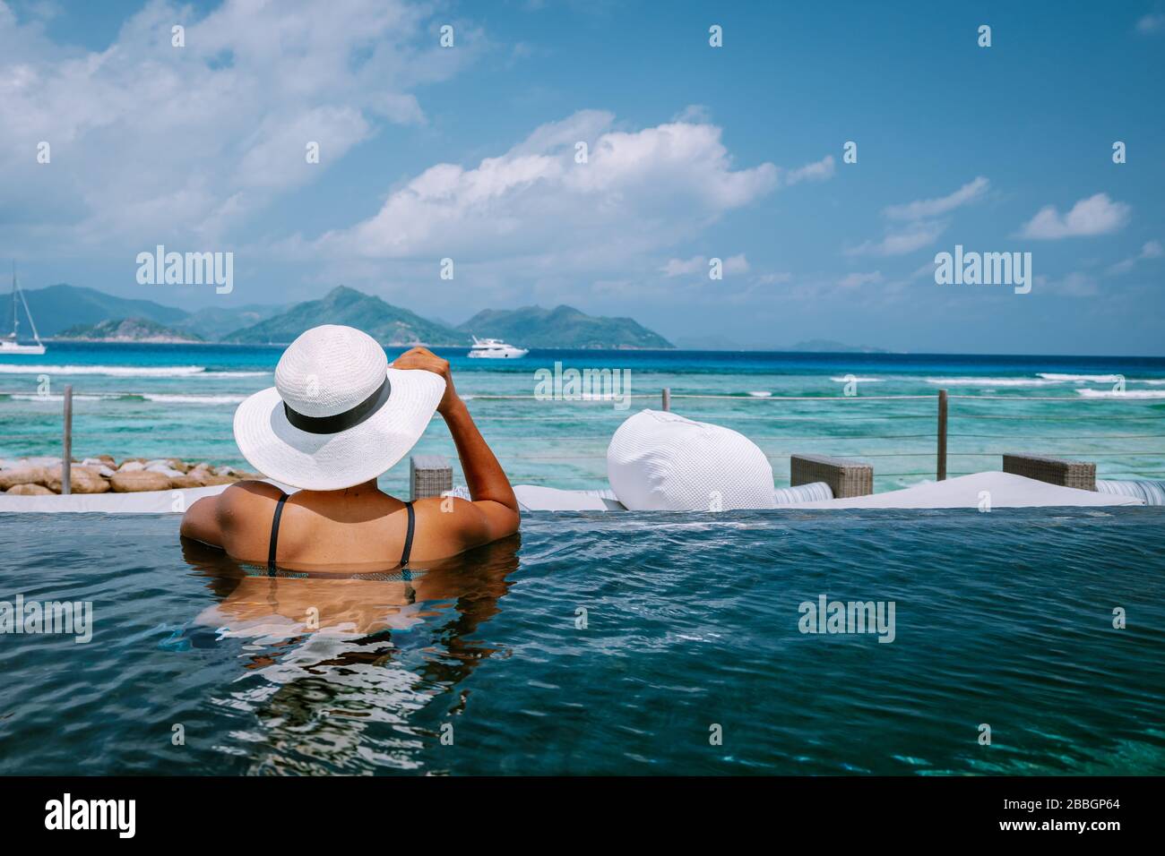 Petite Anse Mahe Seychellen, junge Frau am Strand, mittelalte Asiatin, die am tropischen Strand der Seychellen spaziert Stockfoto