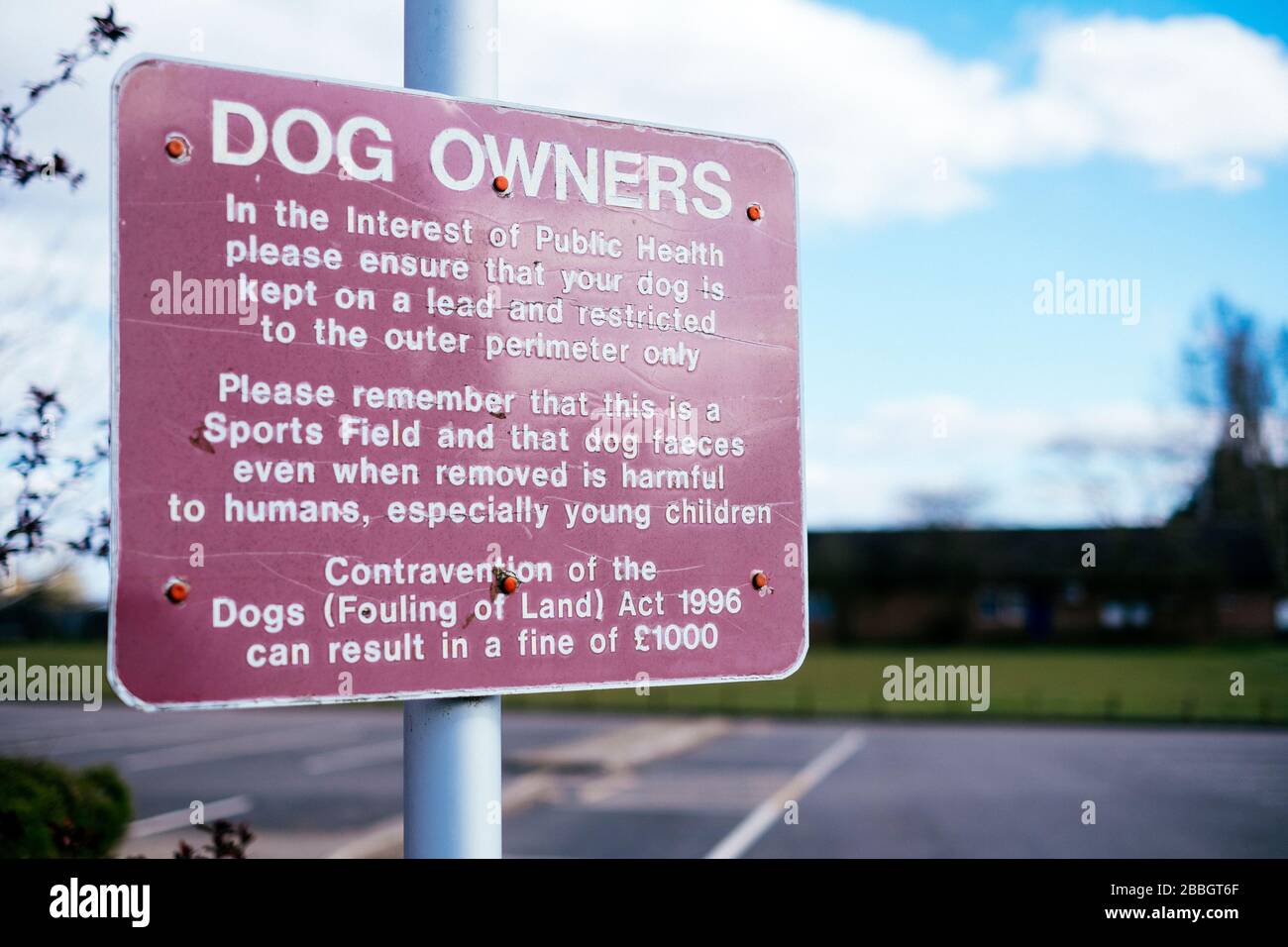 Ein Schild, das Hundebesitzer warnt, ihren Hund auf einem Gemeinschaftssportplatz an der Spitze zu halten Stockfoto