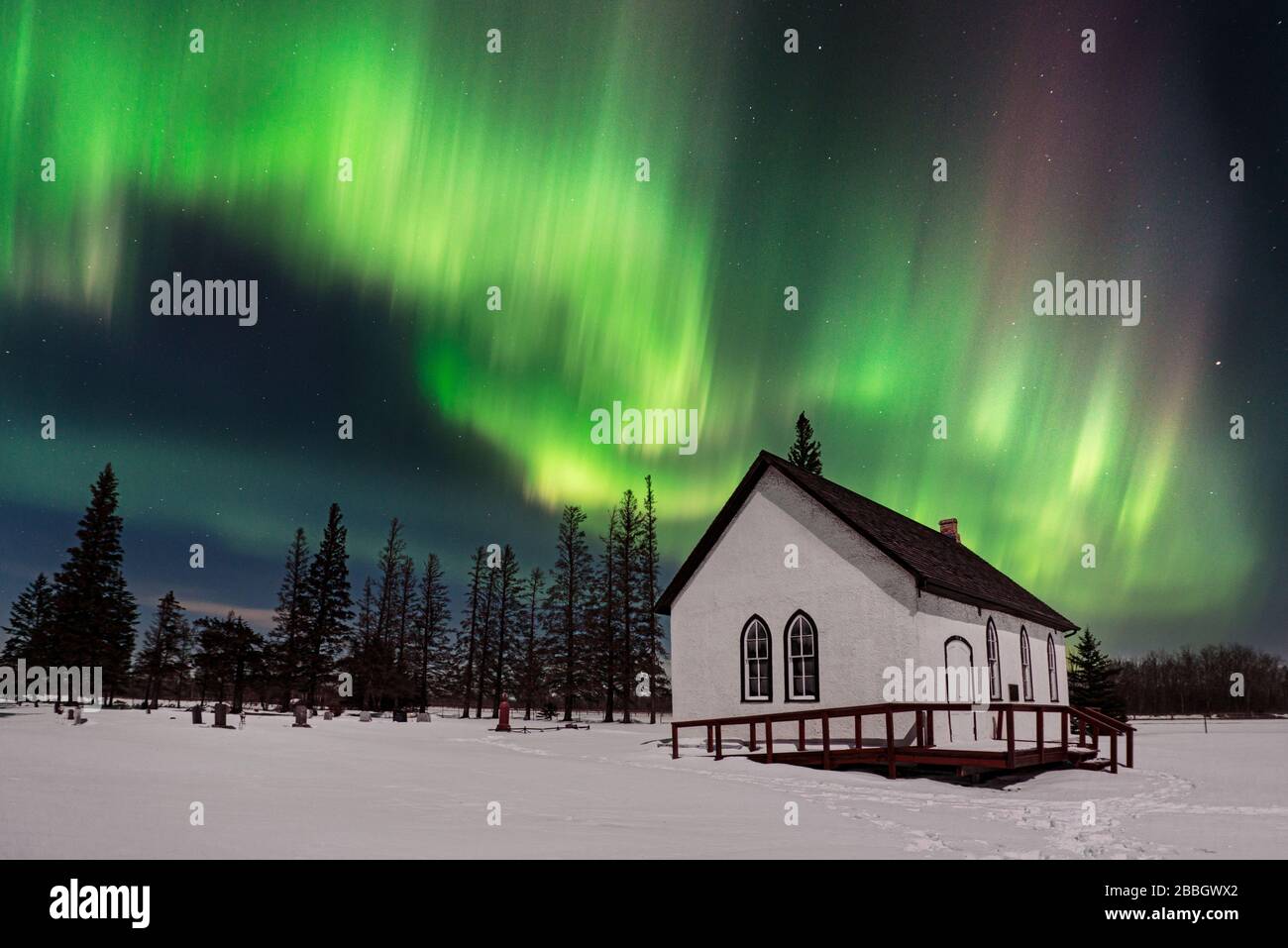 Aurora tanzt über einer alten Kirche in einer mittleren Winternacht im ländlichen Manitoba Kanada Stockfoto