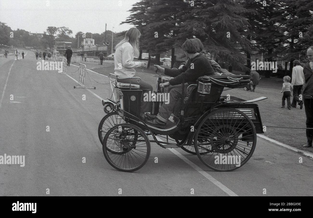 In den 1970er Jahren saßen Menschen auf einem Oldtimer oder Veteranenwagen auf einer Straße auf der historischen Rennstrecke im Crystal Palace Park, South London, England, Großbritannien. Stockfoto