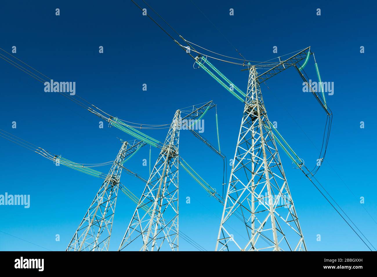 Hochspannungsleitungen mit blauen Himmel im Hintergrund, drei Strommasten Stockfoto