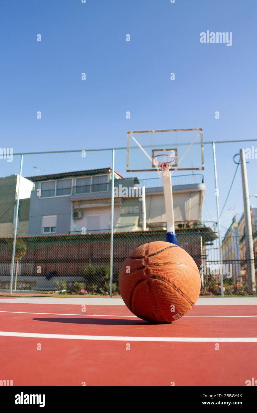 Gebrauchtes Basketball im Vordergrund liegt auf einem Basketballplatz und  einem Basketballkorb mit verschwommenem Hintergrund Stockfotografie - Alamy