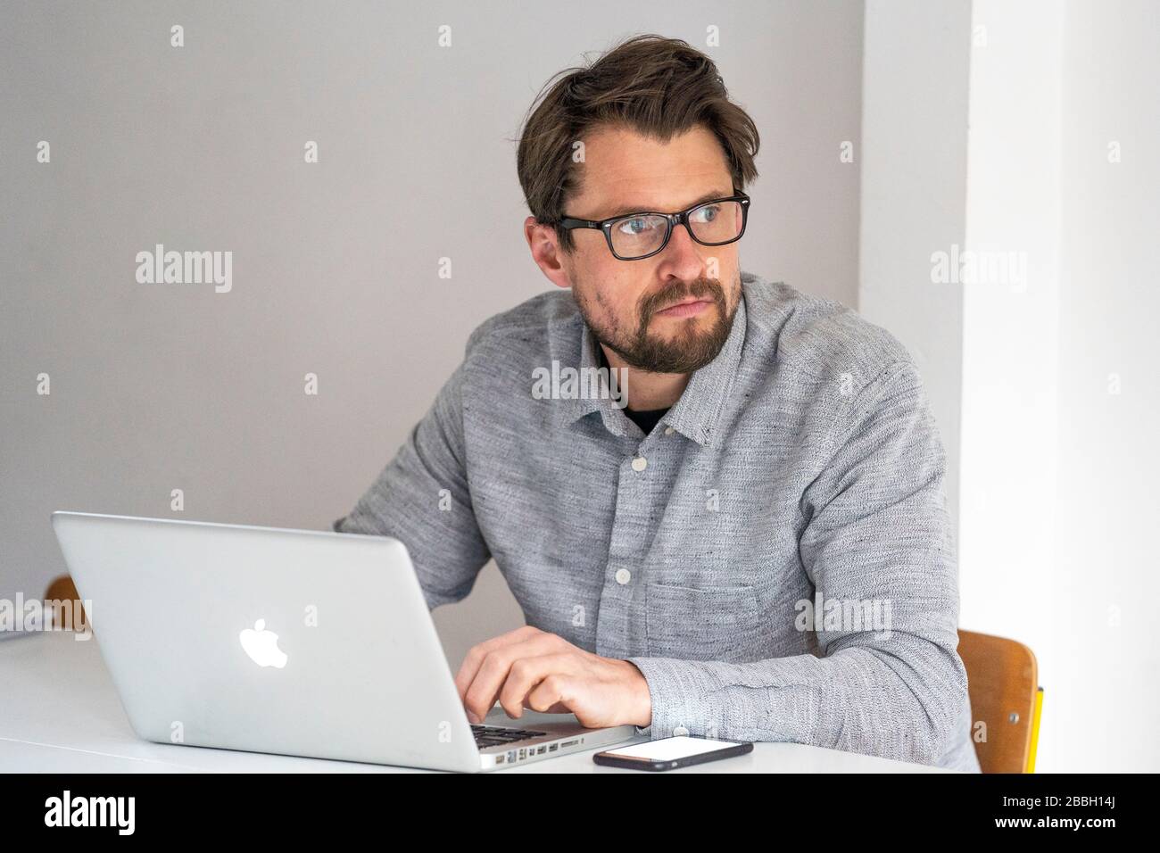 MID 40er-Mann, der von zu Hause aus mit einem Apple-Laptop arbeitet. Stockfoto
