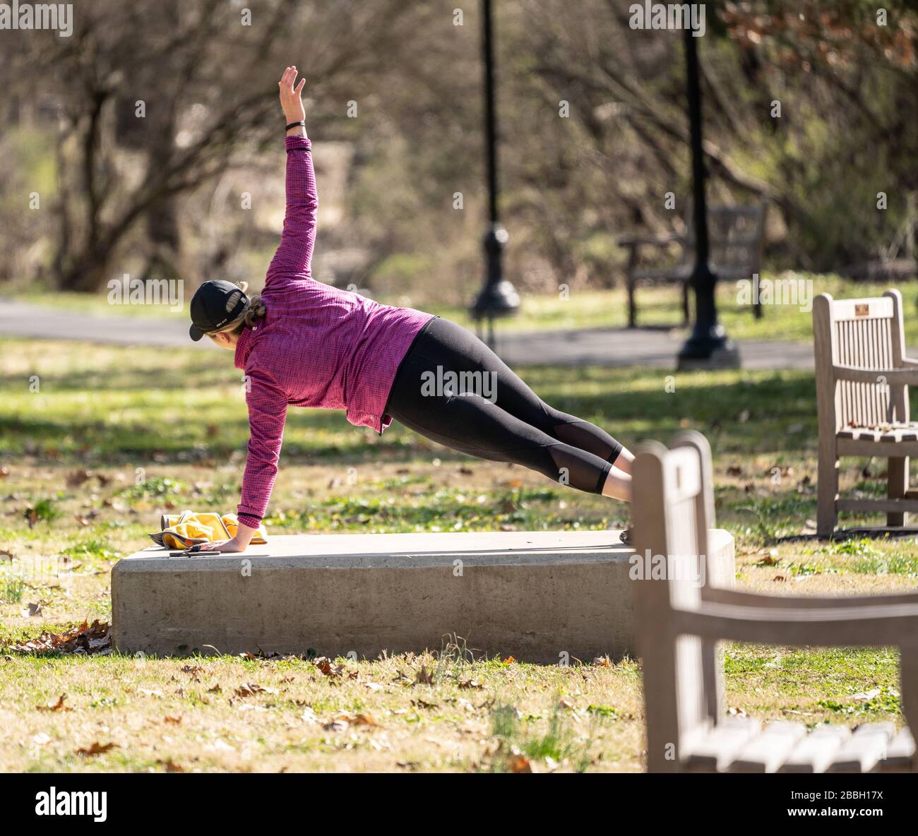 Berks County, Pennsylvania, USA-22. März 2020: Fit Young Woman, die im Freien im öffentlichen Park Seitenplanken macht. Stockfoto