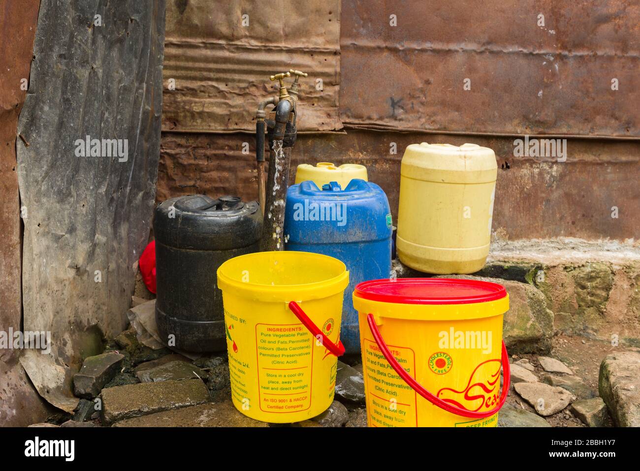 Mehrere Kunststoff-Wasserbehälter rund um einen Wasserhahn im Freien, aus dem Wasser tropft, Nairobi, Kenia Stockfoto