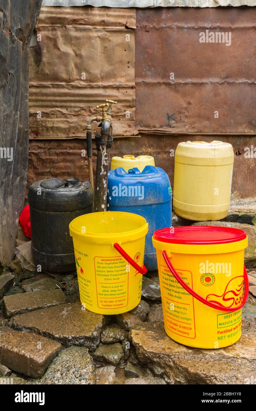 Mehrere Kunststoff-Wasserbehälter rund um einen Wasserhahn im Freien, aus dem Wasser tropft, Nairobi, Kenia Stockfoto