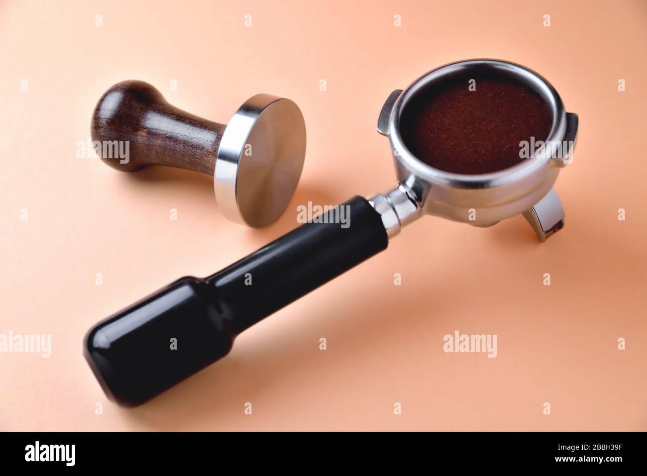 Kaffeehorn mit natürlichem gemahlenem Kaffee und Temperament auf orangefarbenem Hintergrund Stockfoto