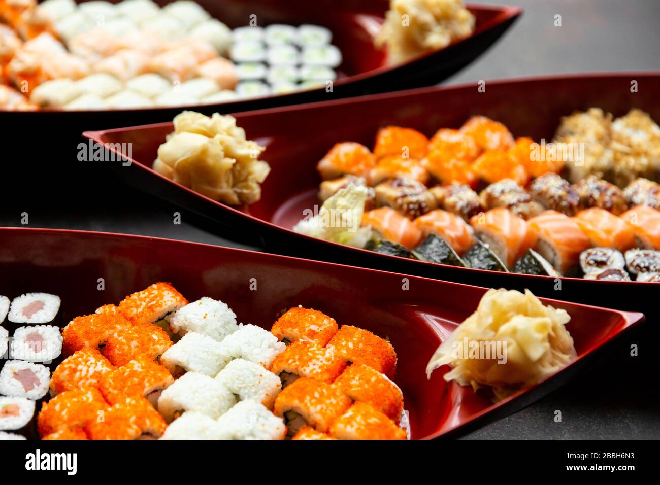 japanische Sushi-Küche. Verschiedene Sushi-Arten werden auf einem Boot aus nächster Nähe serviert. Großer Satz Brötchen auf einem Teller in einem Restaurant. Stockfoto