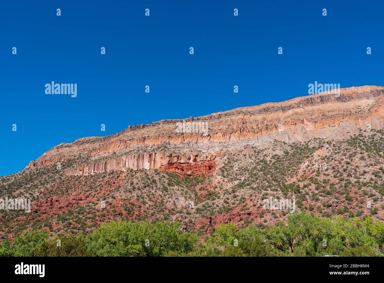 Die Landschaft mit niedrigen Winkeln ist von mehrfarbigen Steinhängen in der Nähe von Jemez Springs, New Mexico, umgeben Stockfoto