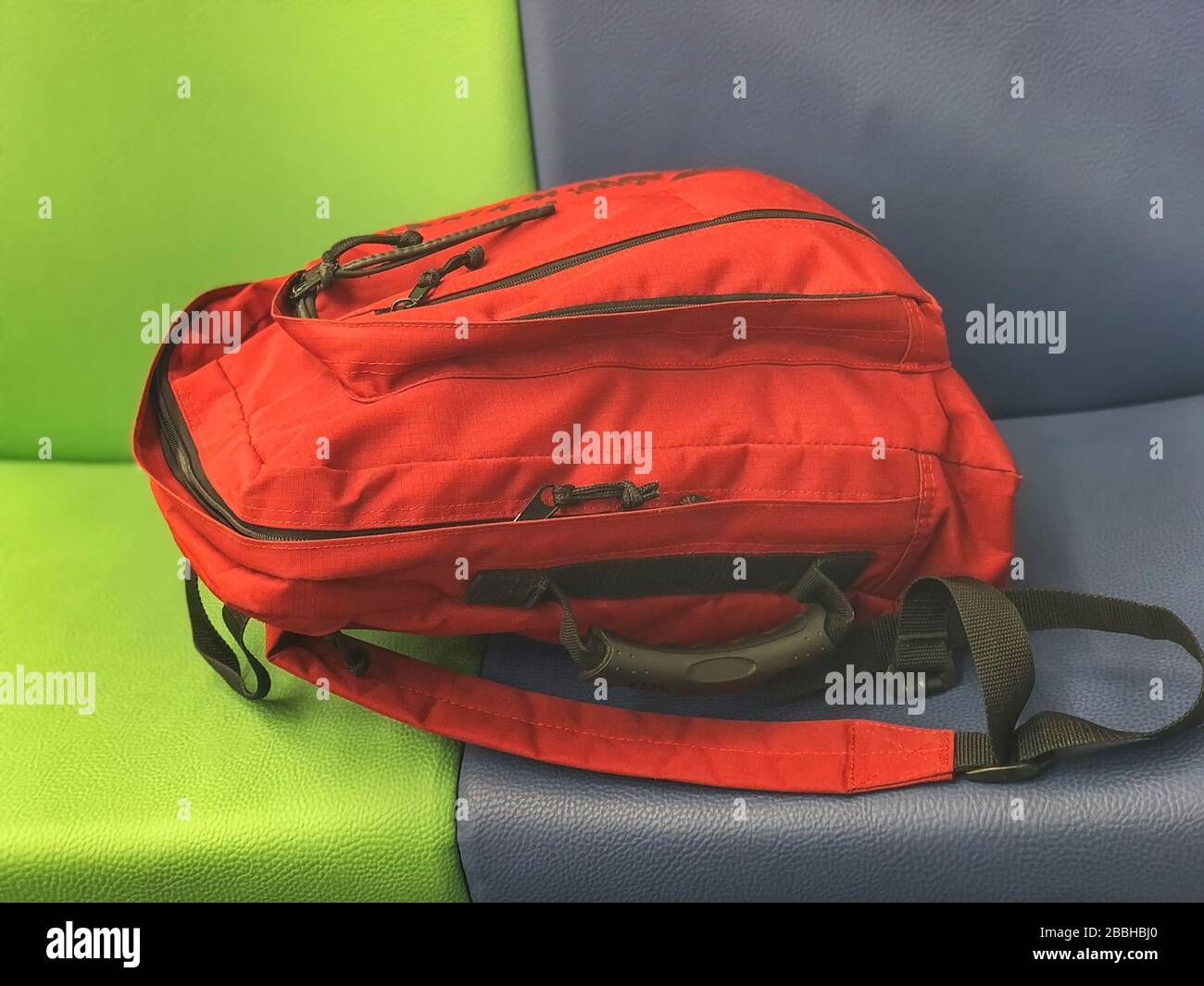 Roter urbaner Jugendrucksack auf einem hellen mehrfarbigen Sitz Stockfoto