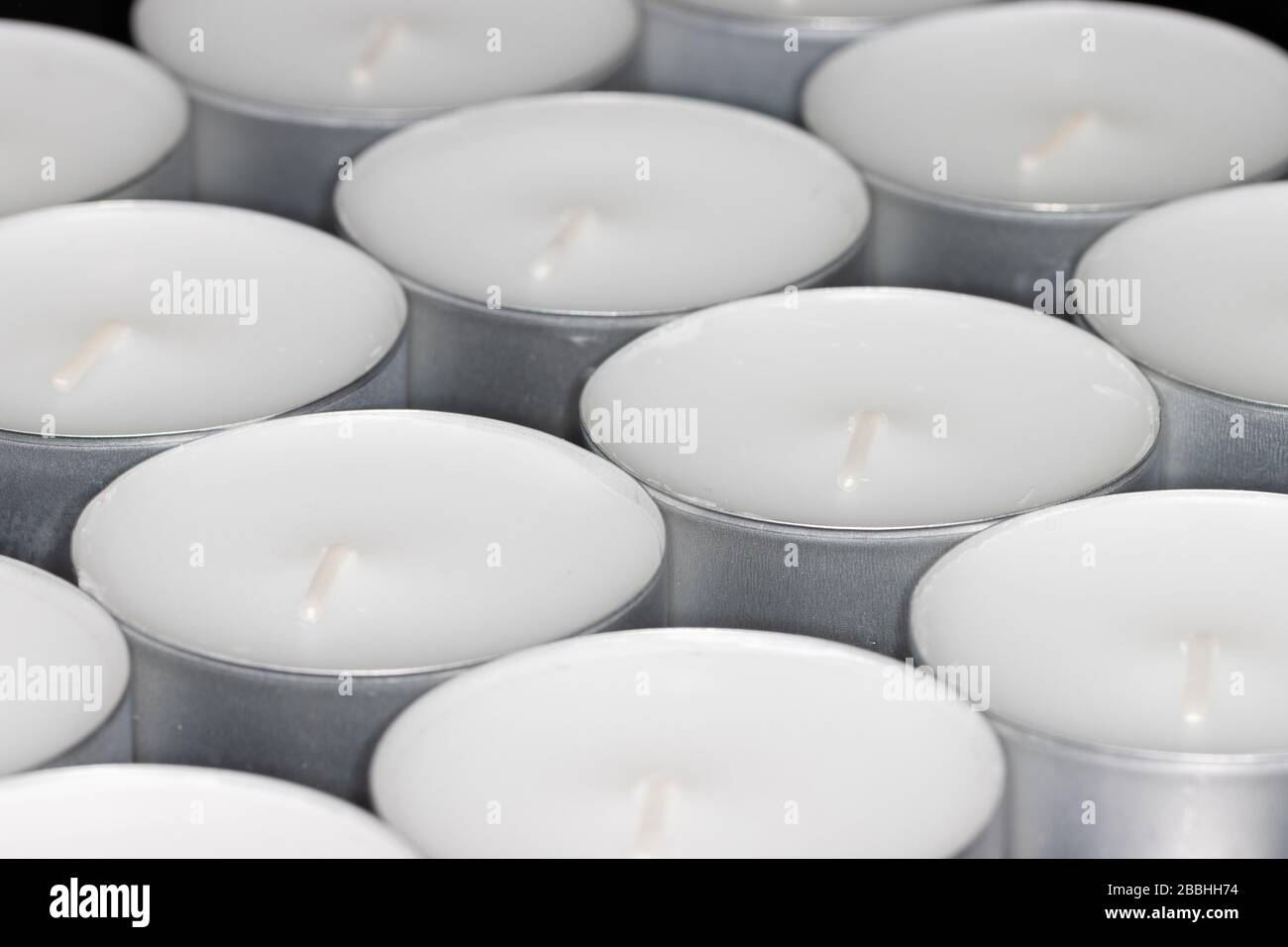 Schicht Teelicht Kerzen auf schwarzem Substrat in diagonalem Winkel aufgenommen Stockfoto