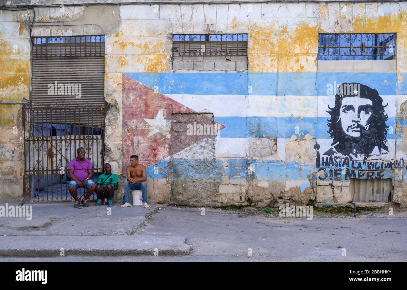 Männer, die sich von Ernesto 'Che' Guevara Wandbild, Havanna Vieja, Kuba entspannen Stockfoto