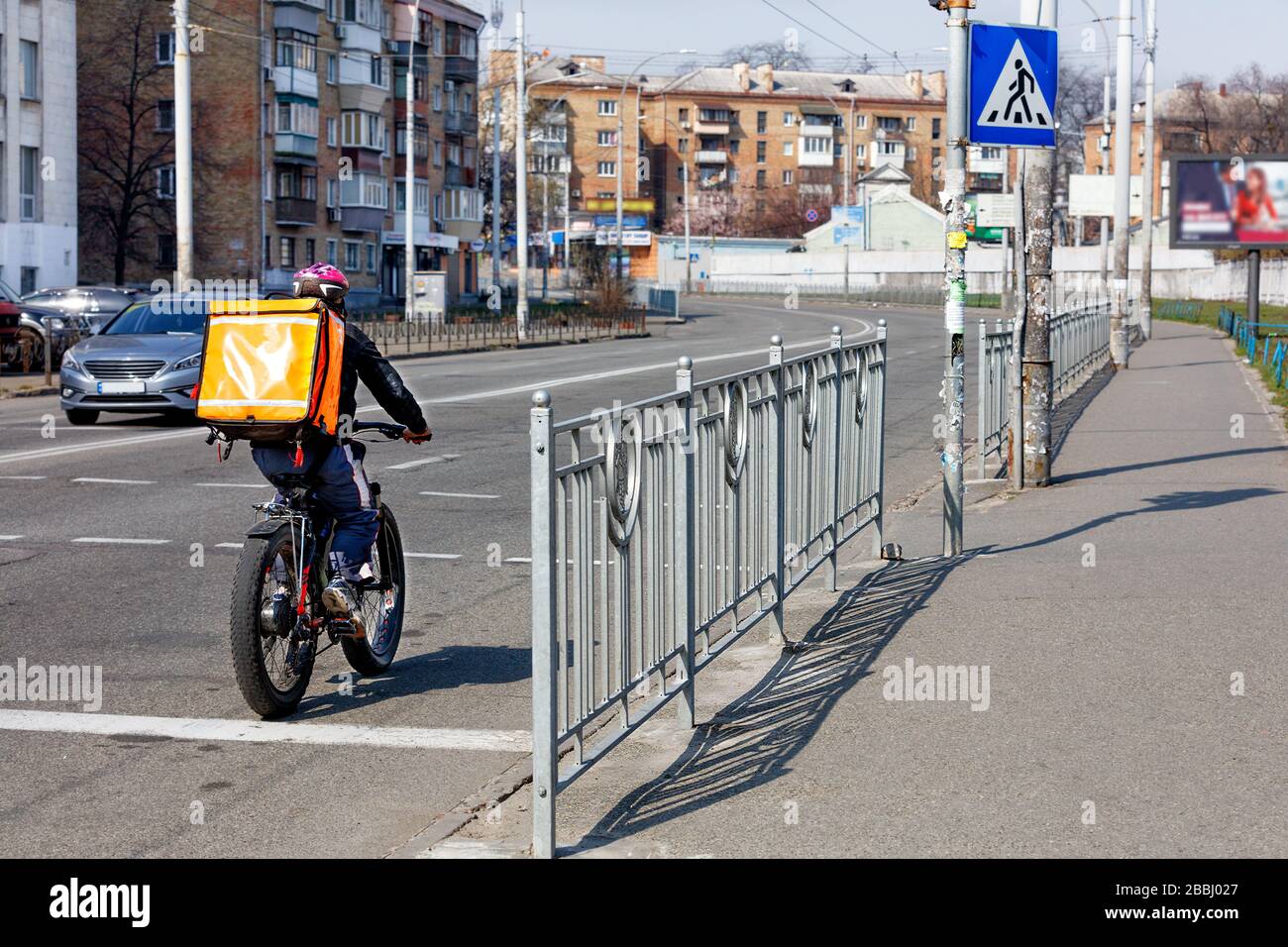 Ein Mann bewegt sich auf einem elektrischen Fahrrad entlang der Fahrbahn auf dem Bürgersteig einer Stadtstraße - ein modernes Konzept der Bewegungsfreiheit. Stockfoto