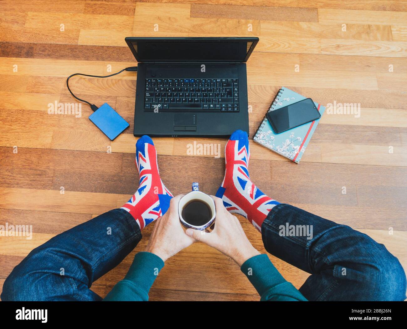 Mann mit union Jack Flag Socke auf Holzboden mit Laptop. Arbeiten von zu Hause, Selbstisolierung, soziale Distanzierung, Coronavirus... Konzept Stockfoto