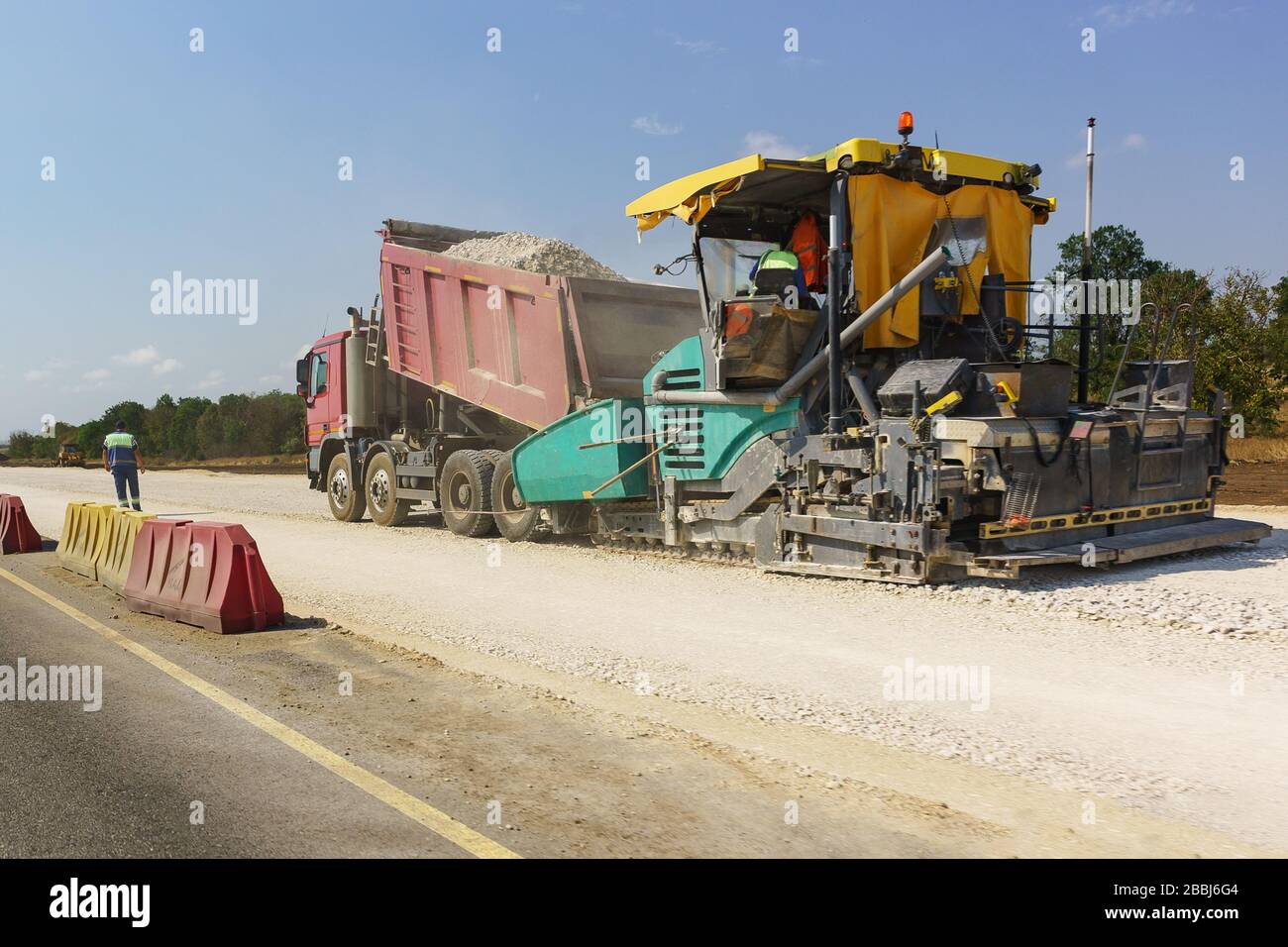Bau einer neuen modernen Autobahn Tavrida auf der Krim. Rückfüllung von Trümmern aus dem Stapler in die Kapazität des Vibrierfertigers. Dusty Sunny Sum Stockfoto