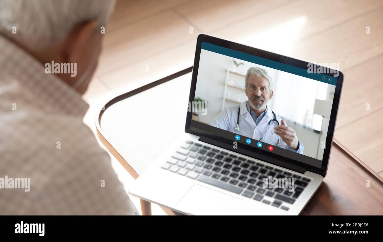 Rückansicht des reifen Mannes mit Hilfe der Laptop-Webcam eine Videoanruf-Beratung mit dem männlichen Arzt, Nahaufnahme von älteren männlichen Patienten sprechen Sie mit GP oder Phys Stockfoto