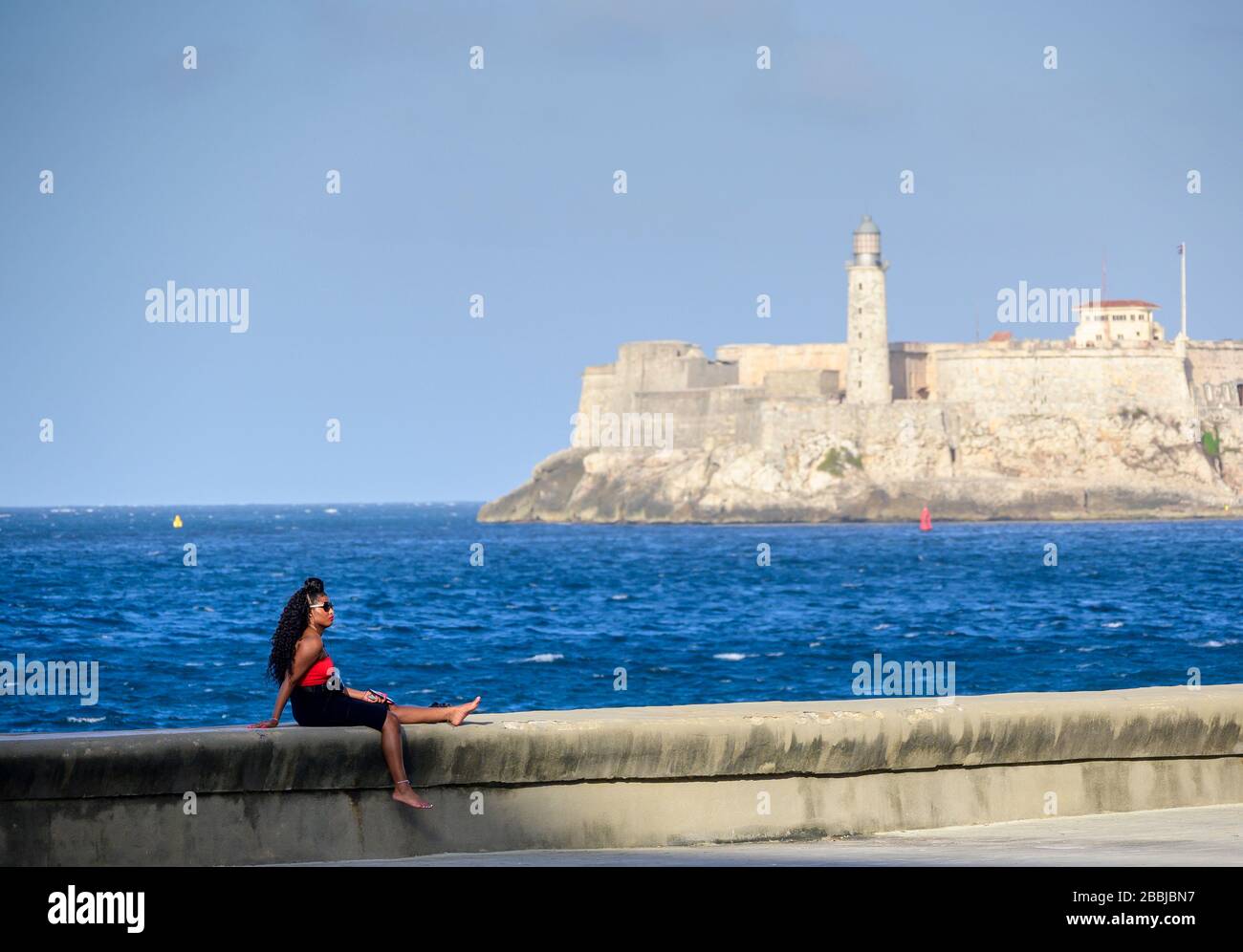 Frau auf dem Malecon, mit Morro Castle Beyond, Centro, Havanna, Kuba Stockfoto