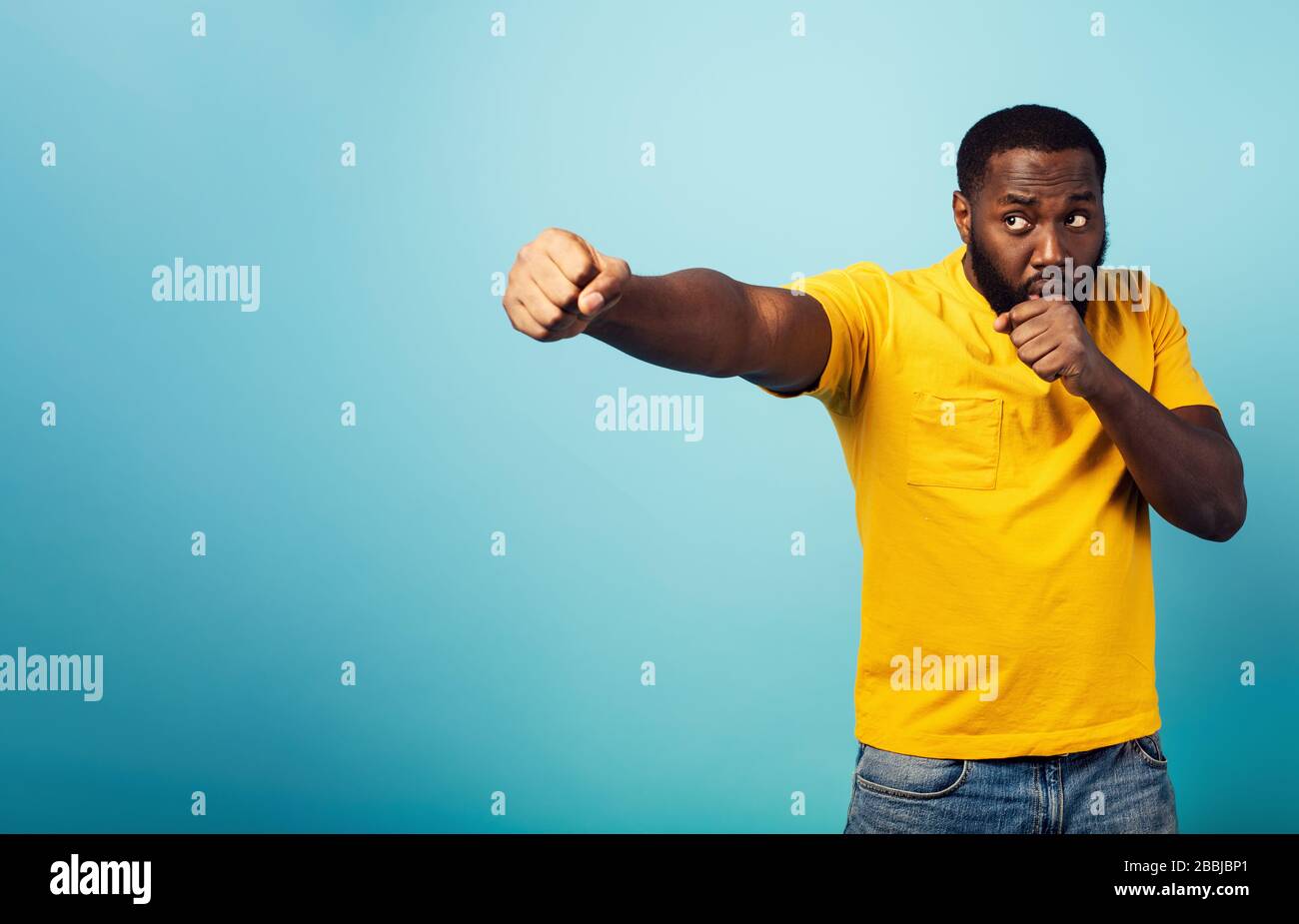 Der wütende Mann greift mit einem Schlag etwas an. Blauer Hintergrund Stockfoto