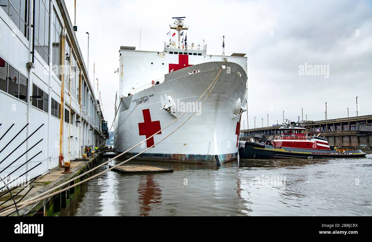 New York, Vereinigte Staaten von Amerika. März 2020. Das US Navy Military Sealift Command Hospitalschiff USNS Comfort wird nach der Ankunft im Hafen von New York am 31. März 2020 in New York City, New York, mit Schleppbooten in das Dock am Pier 90 geschoben. Der Comfort setzt sich zur Unterstützung der COVID-19-Reaktionsbemühungen der Nation in die Stadt ein. Kredit: Kenneth Wilsey/FEMA/Alamy Live News Stockfoto