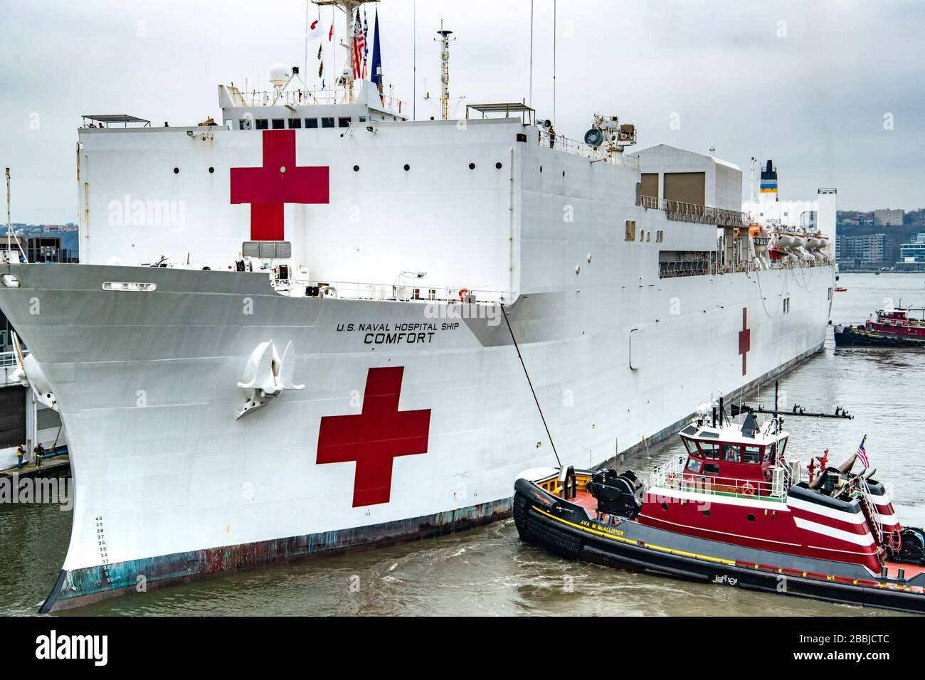 New York, Vereinigte Staaten von Amerika. März 2020. Das US Navy Military Sealift Command Hospitalschiff USNS Comfort wird nach der Ankunft im Hafen von New York am 31. März 2020 in New York City, New York, mit Schleppbooten in das Dock am Pier 90 geschoben. Der Comfort setzt sich zur Unterstützung der COVID-19-Reaktionsbemühungen der Nation in die Stadt ein. Kredit: Kenneth Wilsey/FEMA/Alamy Live News Stockfoto