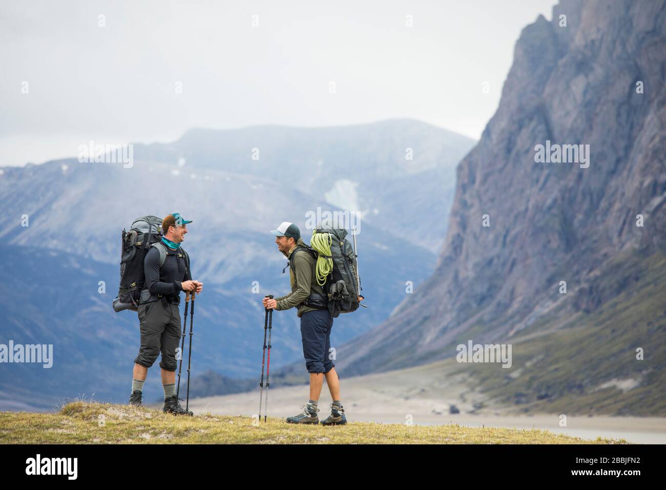Zwei Freunde halten an, um beim Rucksackwandern in den Bergen zu lachen. Stockfoto