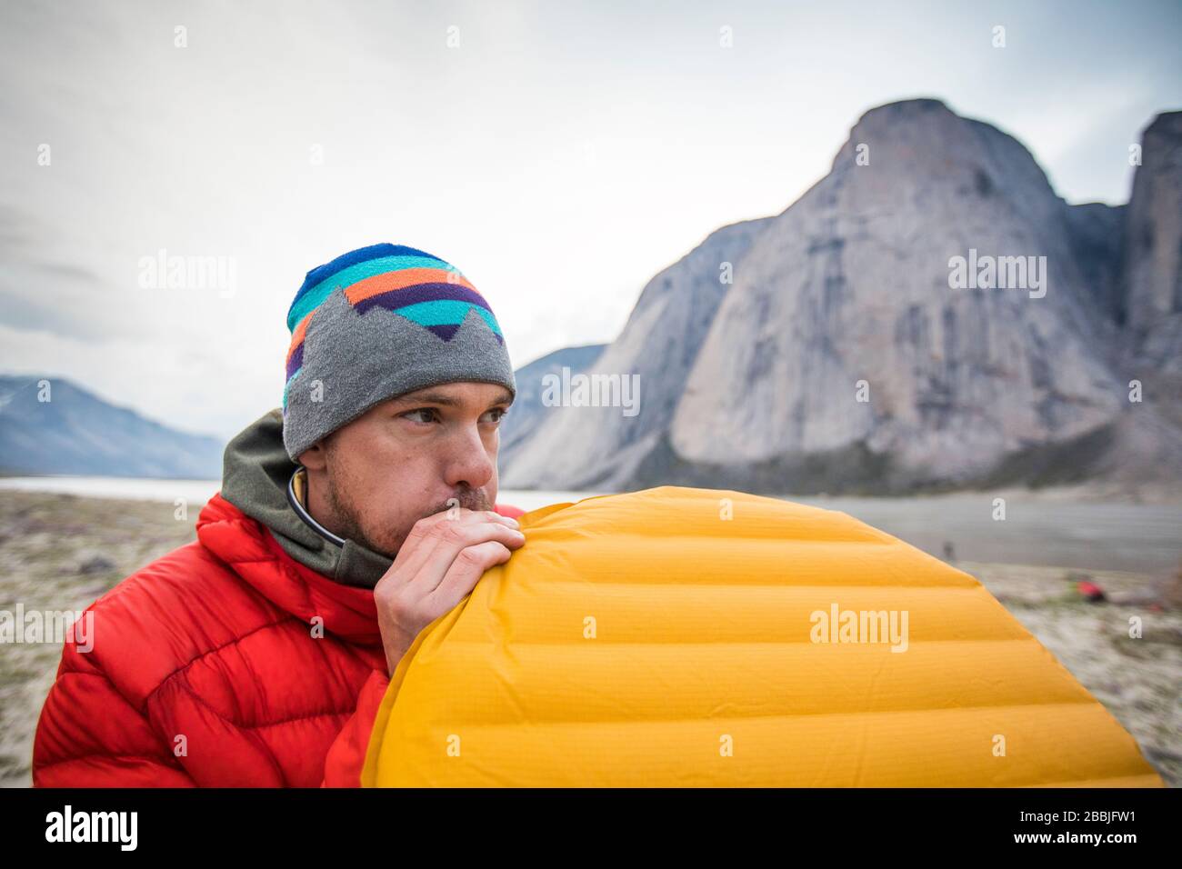 Kletterer bläst Luftmatratze beim Campen in den Bergen. Stockfoto