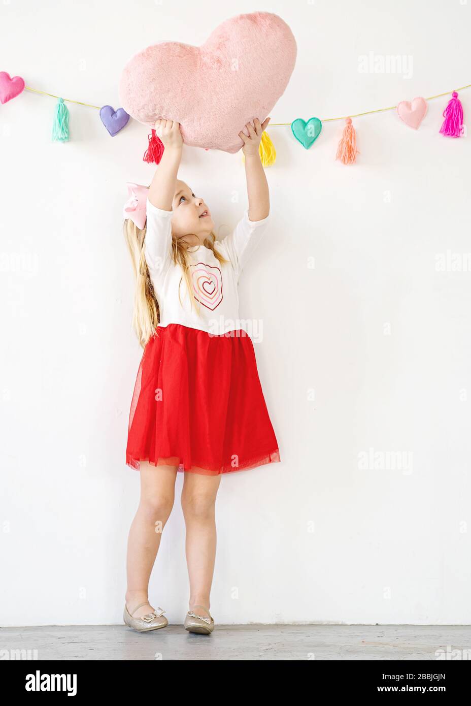 Nettes junges Mädchen mit rosa Herz Kissen bis über den Kopf Stockfoto