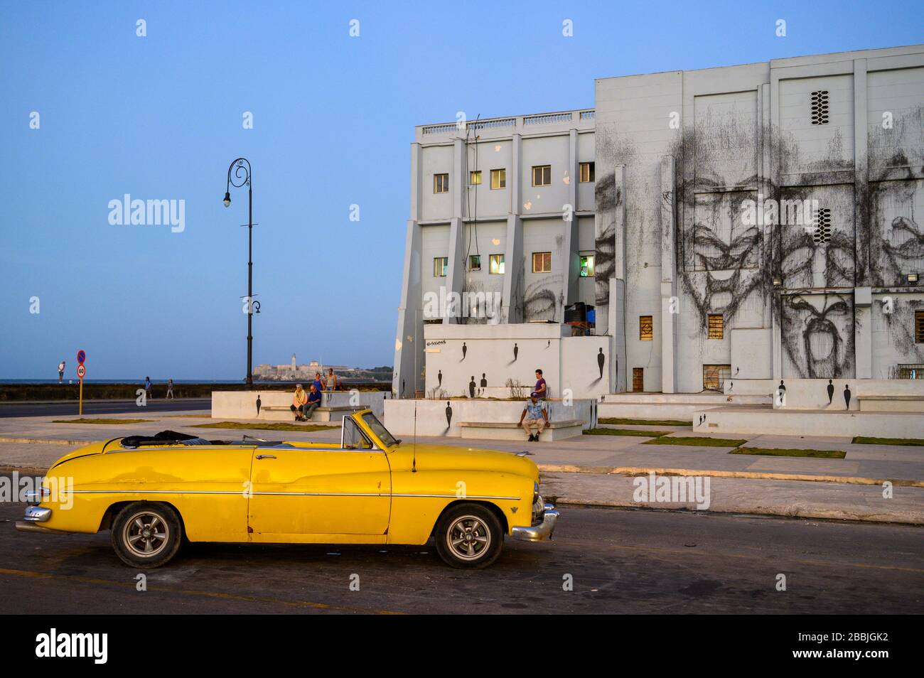 Oldtimer in der Abenddämmerung mit Wandbild am Bau hinter, Centro, Havanna, Kuba Stockfoto
