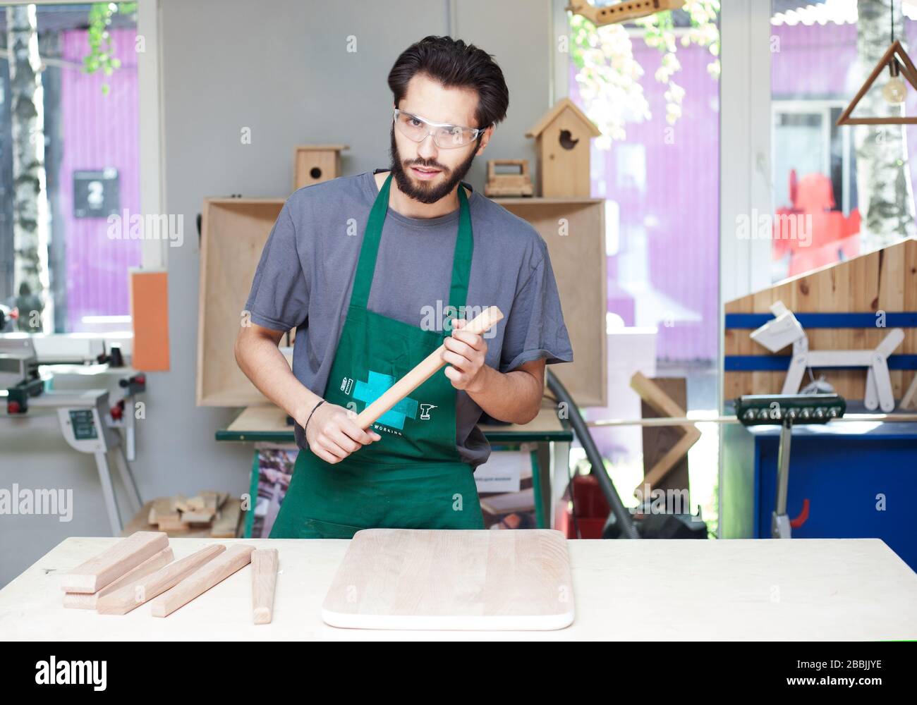 Das Porträt eines Schreinermeisters mit Bart in Arbeitskleidung in einer Schreinerei beginnt mit der Arbeit. Stockfoto