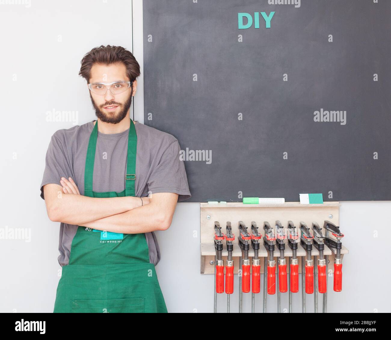 Der Tischlermeister mit Bart in Arbeitskleidung in einer Schreinerei befindet sich auf der Graphitplatte Stockfoto