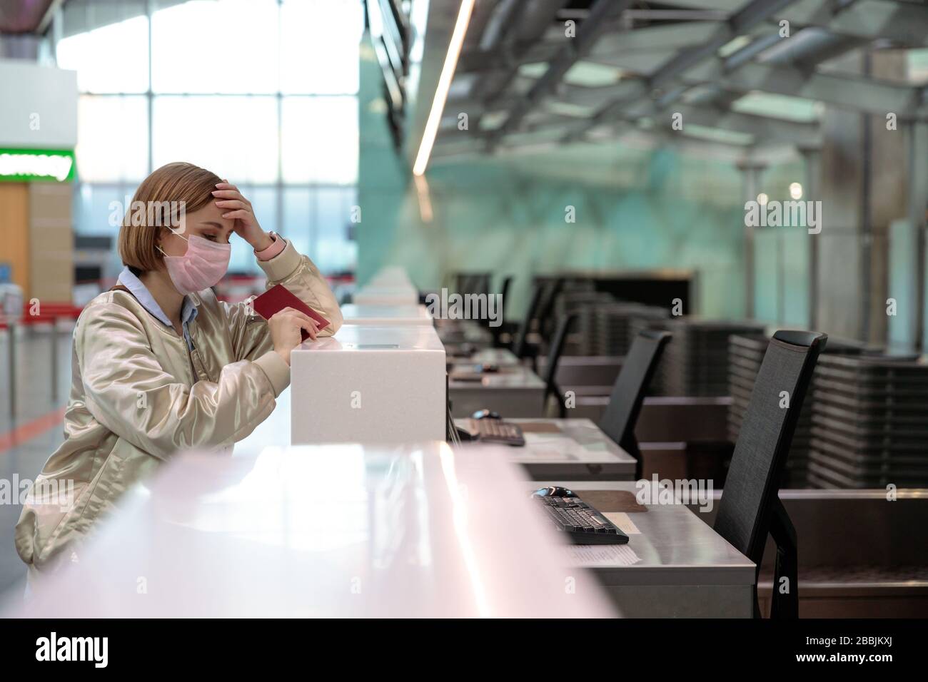 Frau mit Gepäck über Flugannullierung, steht an leeren Check-in-Schaltern am Flughafenterminal wegen Coronavirus-Pandemie/Covid-19-Ausbruch Trave Stockfoto