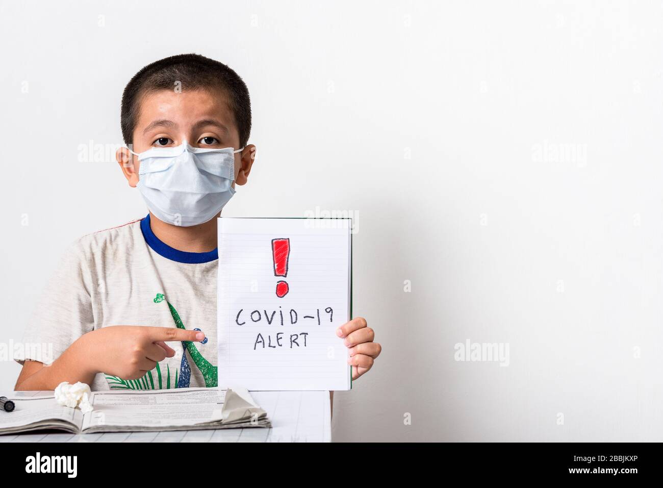Corona Virus/Home Schooling Konzeptbild mit einem jungen asiatischen Jungen, der Buch in der Hand hält und auf die Botschaft zeigt - Gesundheitswesen/Pandemie-Image Stockfoto