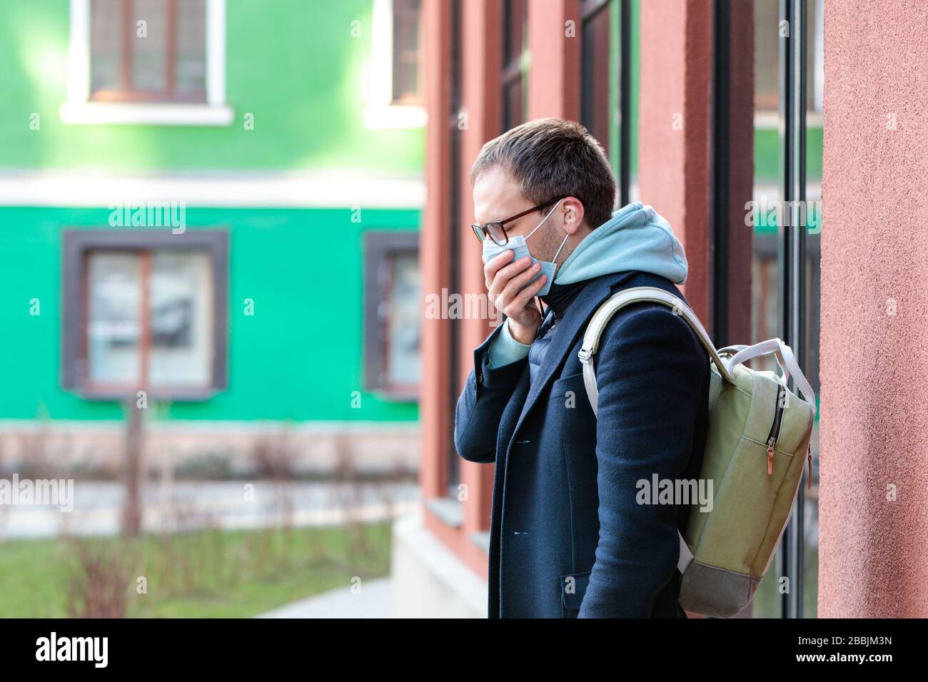 Mann in einer Brille, der sich im Freien krank fühlt, hustet, Schutzmaske gegen übertragbare Infektionskrankheiten trägt, Pollen allergie, Schutz gegen Stockfoto