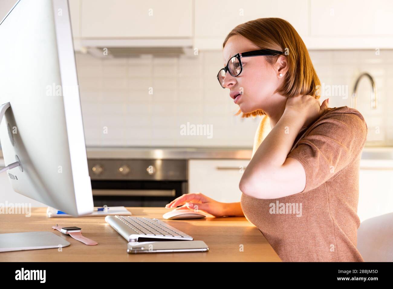Freiberuflerin in beigefarbener Oberseite leidet nach langer Arbeit am Computer während der Zeit der Selbstisolierung und der Telearbeit zu Hause unter Schmerzen im Hals. C Stockfoto