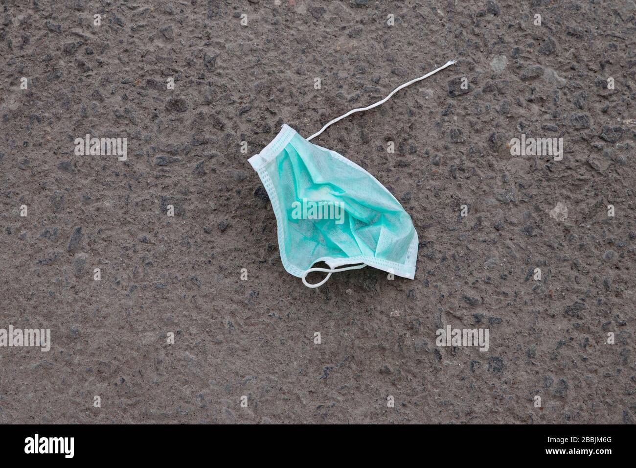 Schmutzig gebrauchte chirurgische Gesichtsmaske zum Schutz von Coronavirus auf Asphalt. Entsorgung medizinischer Abfälle. Draufsicht. Allergiesaison, Staubluft. Stockfoto
