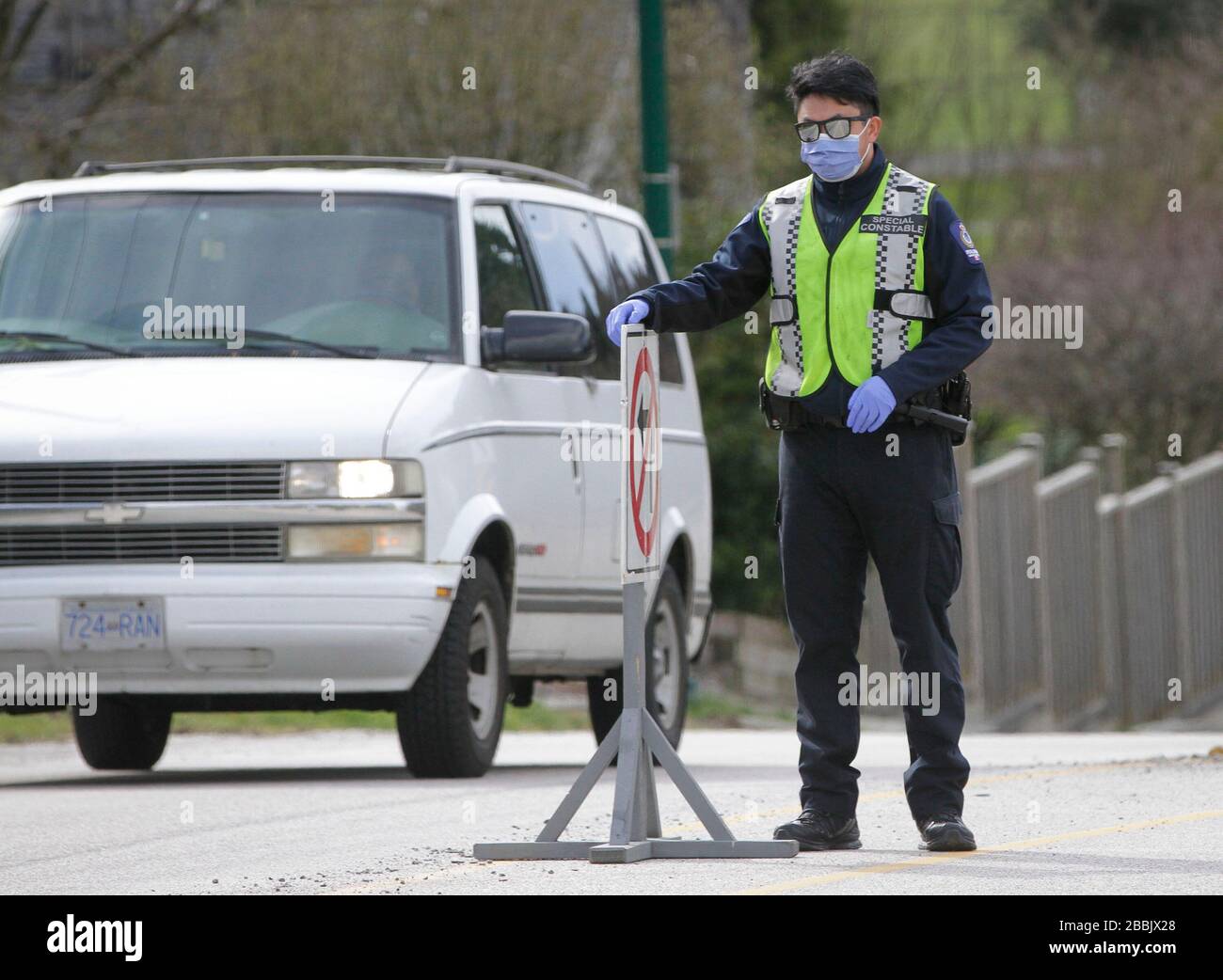 Vancouver, Kanada. März 2020. Ein Polizeibeamter leitet den Verkehr außerhalb eines COVID-19-Testgeländes in Vancouver, Kanada, am 31. März 2020. Mehrere Satellitenstandorte rund um die Städte betreiben 7 Tage die Woche und bieten einen Drive-Through-COVID-19-Test an. Kredit: Liang Sen/Xinhua/Alamy Live News Stockfoto