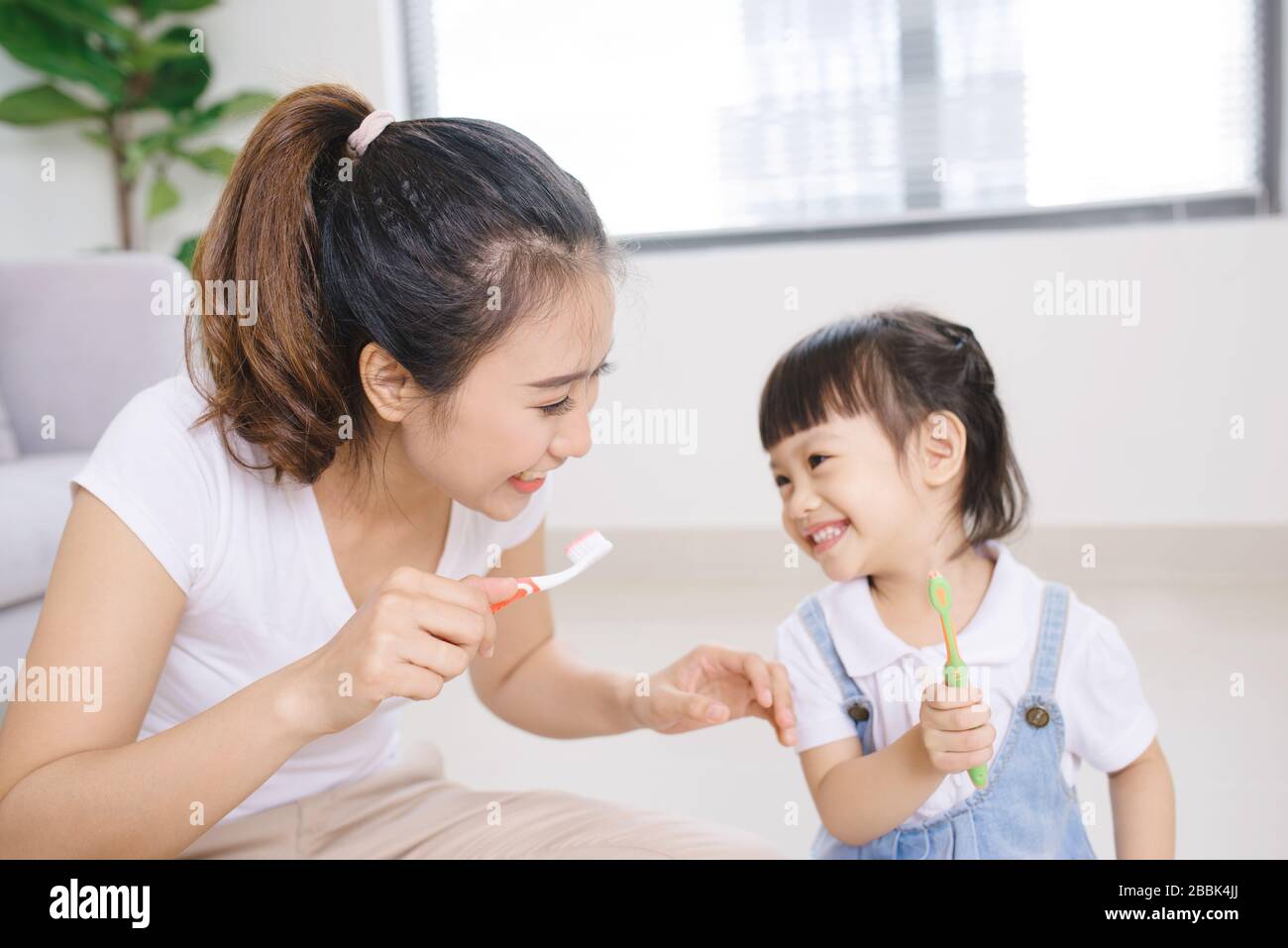 Mutter unterrichtet die Zähne der Kindertochter, die zu Hause putzt Stockfoto