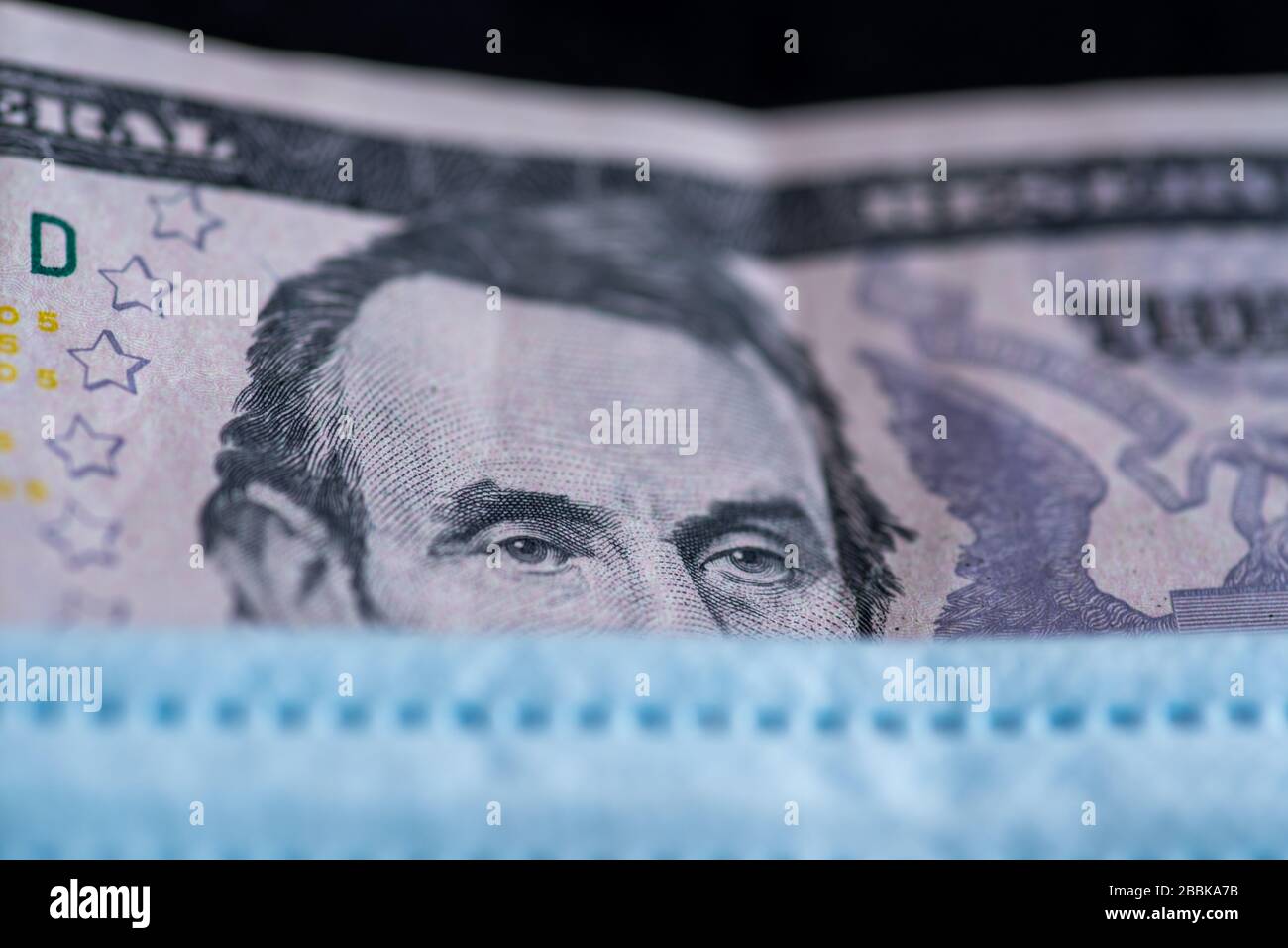 Banknotizen unter Gesichtsmaske - Symbol für die globale Corona-Virus-Pandemie, die sich auf die Wirtschaft auswirkt Stockfoto