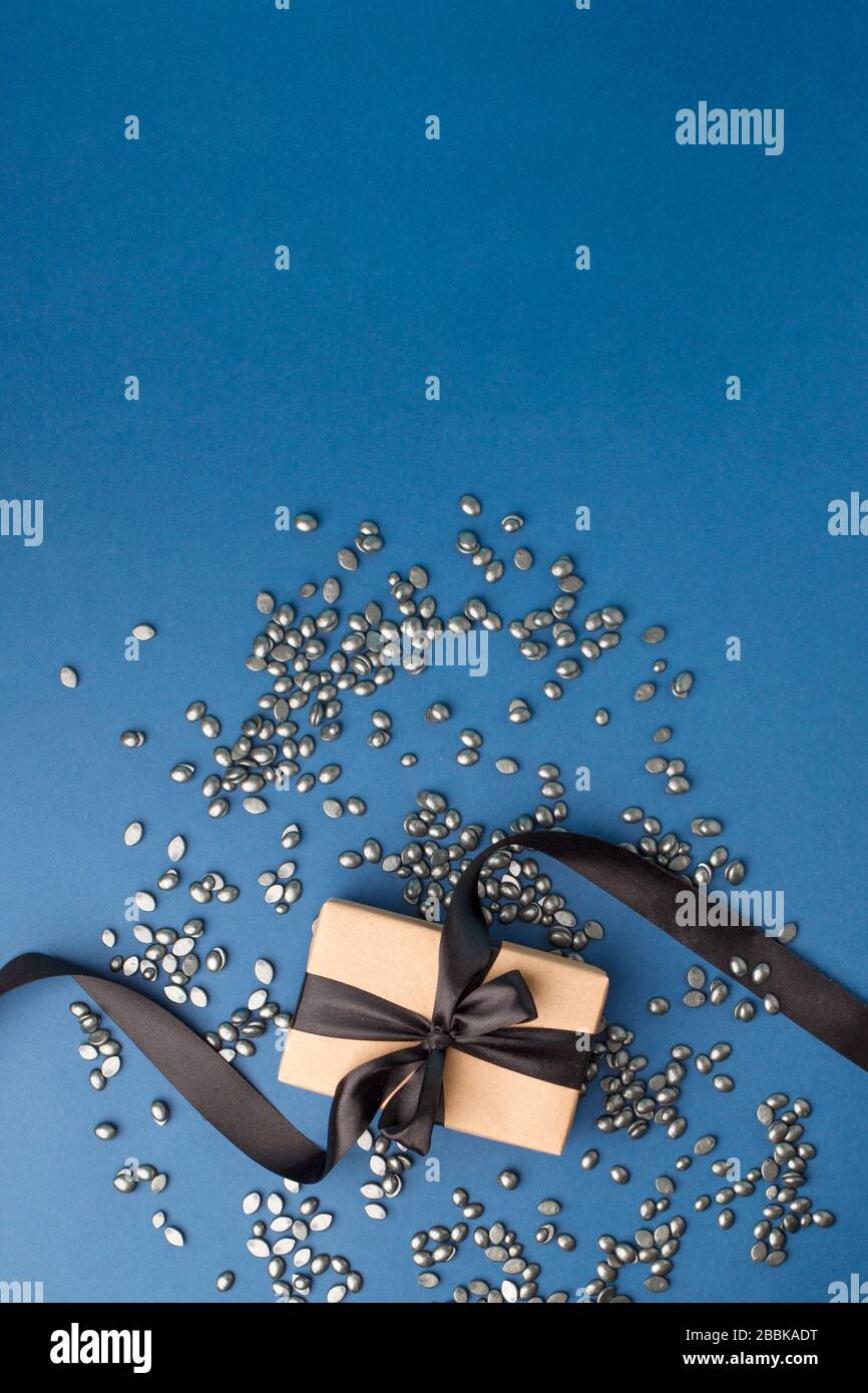 Schwarzes Perlkornwachs für Depilation auf klassischem blauen Hintergrund mit Geschenkbox. Kopierbereich, Banner, Flyer, Coupon minimale Textur. Das Konzept der Promo Stockfoto