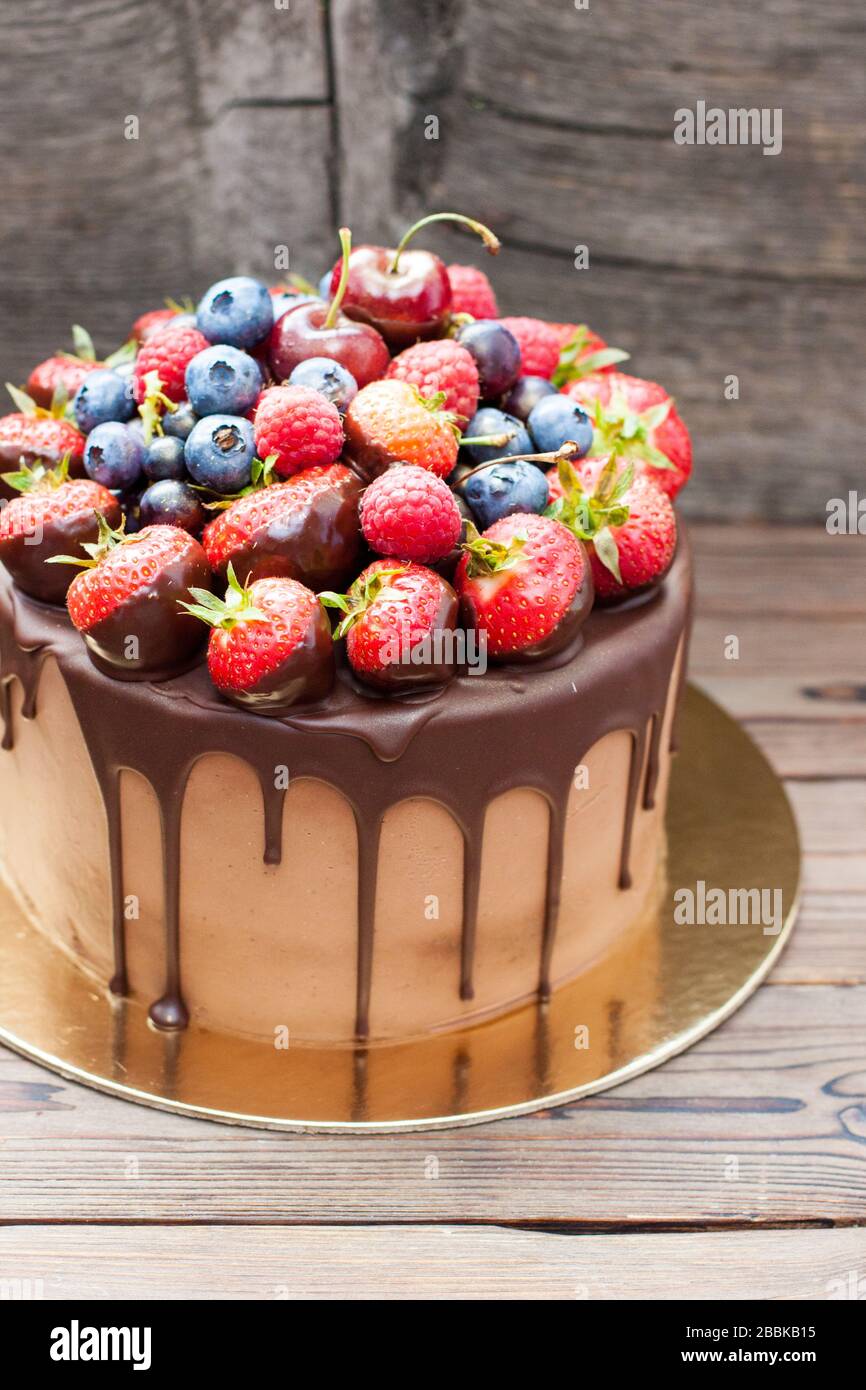 Schokoladenkuchen mit geschmolzener dunkler Schokolade und verschiedenen frischen Sommerbeeren. Stockfoto