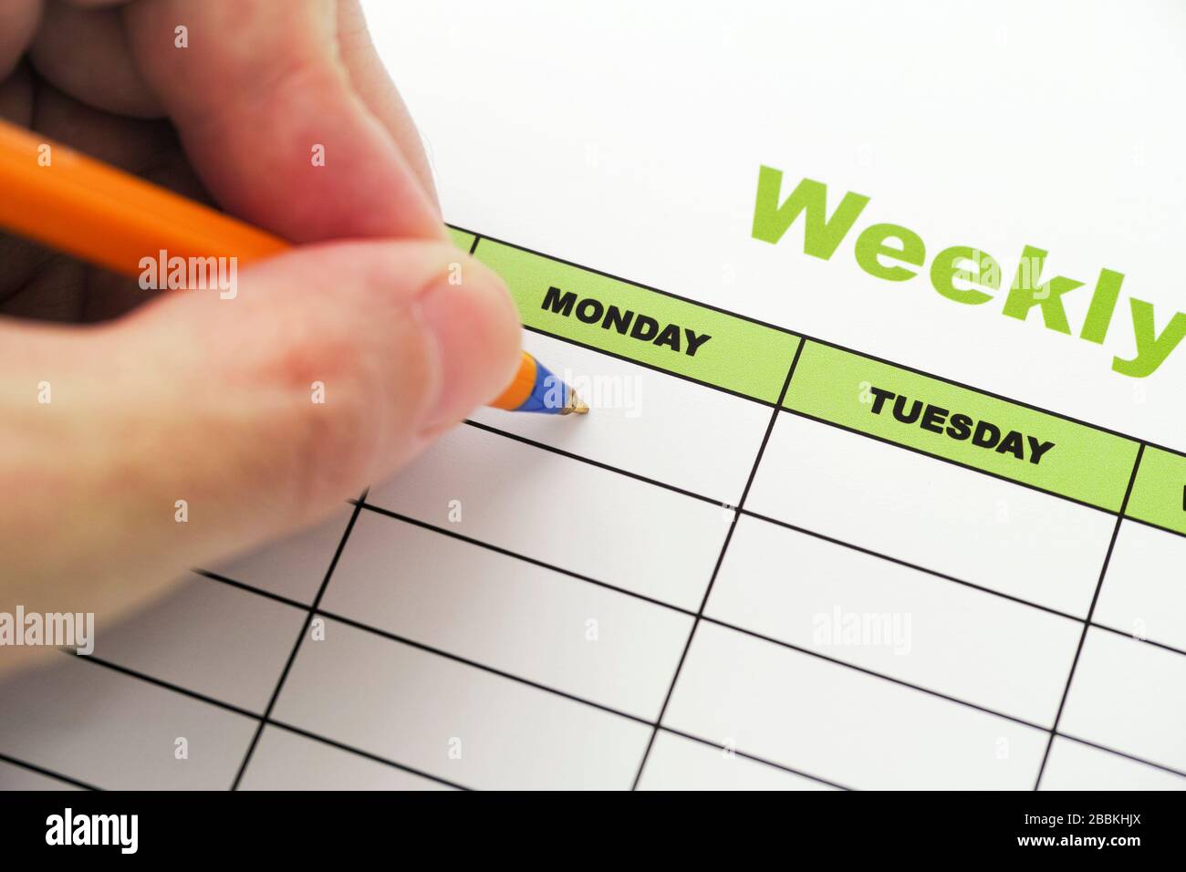Person, die wöchentlich einen Zeitplan mit Kugelschreiber schreibt. Nahaufnahme. Stockfoto