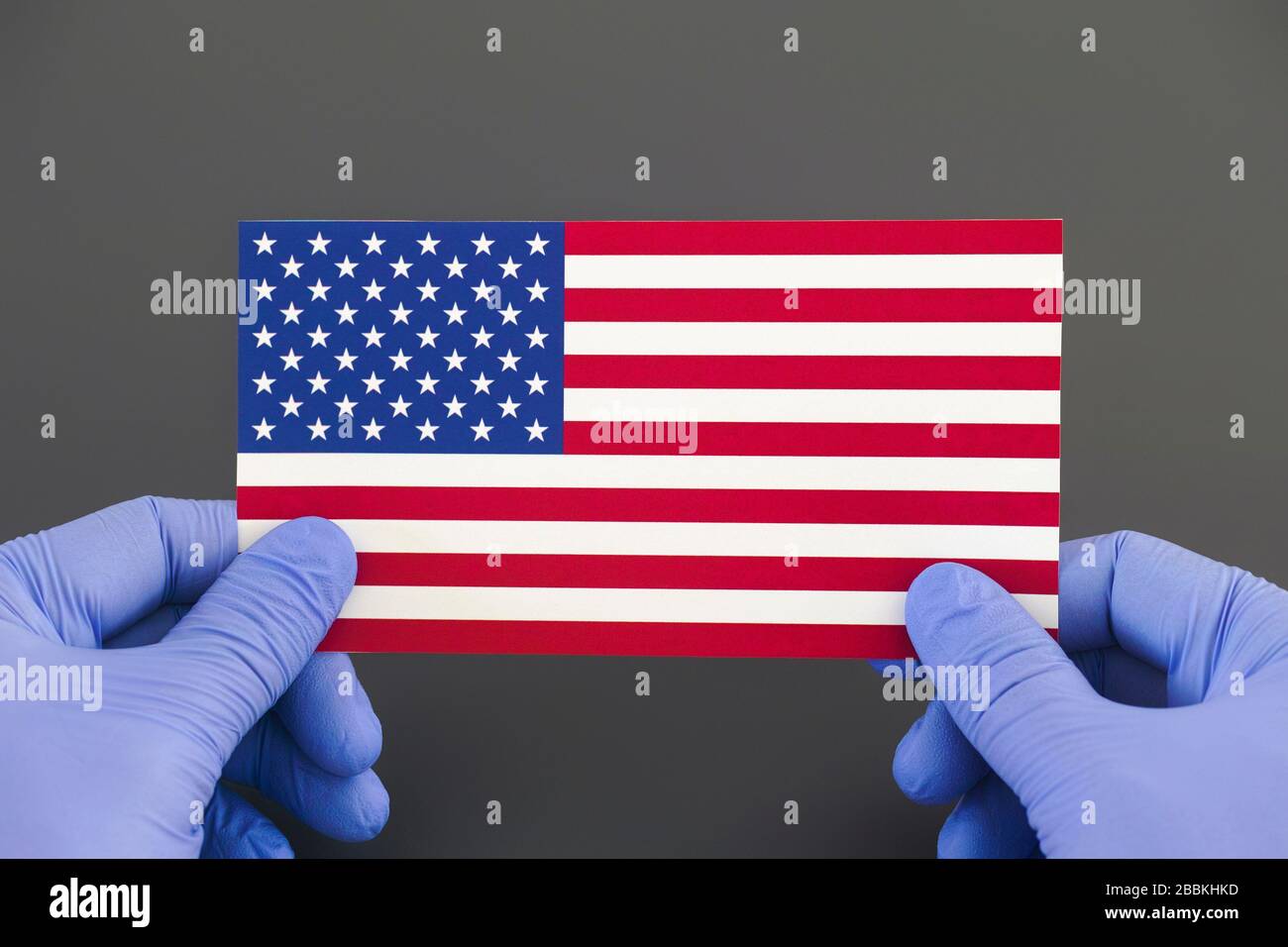 Person, die medizinische Handschuhe trägt, die Flag of the United States in seinen Händen halten. Coronavirus-Ausbruch und Pandemie-Konzept. Stockfoto