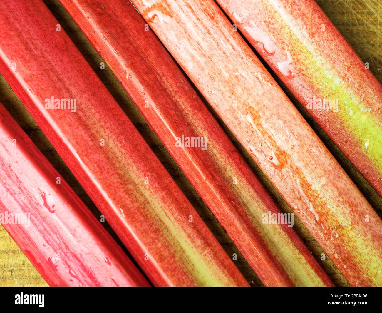 Frische, hausgemachte Rhabarbenstiele auf einem Holzhackbrett Stockfoto